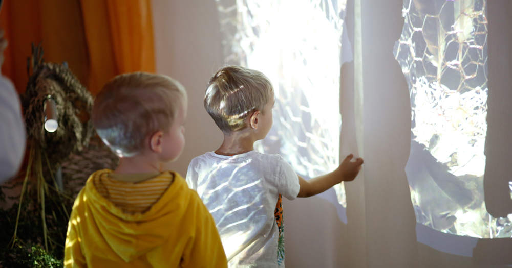 Zwei Jungen blicken ein an die Wand projeziertes Bild an