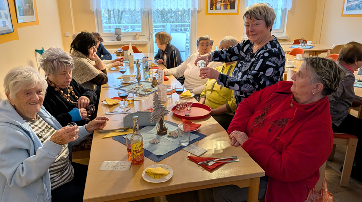 Viele Frauen sitzen an einem Tisch und feiern gemeinsam Weihnachten.