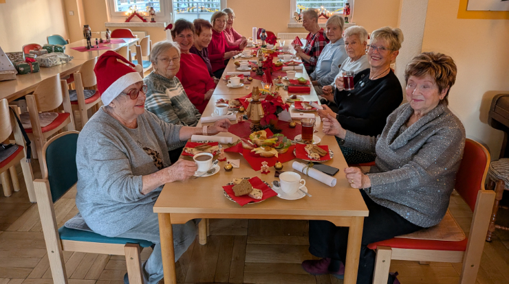 Viele Frauen sitzen an einem Tisch und feiern gemeinsam Weihnachten.